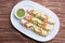 Mexican flutes, golden tacos. Traditional Mexican food. Traditional Mexican tacos with tomato, avocado and green hot sauce. Gourme