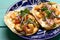 Mexican food. Shrimp tacos with melted cheese and poblano pepper called gobernador on turquoise background