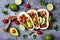 Mexican grilled chicken tacos with avocado, tomato, onion on rustic stone table. Recipe for Cinco de Mayo party.