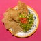 Mexican guacamole with pork chicharron on pink background