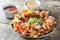 Mexican nachos with beef, guacamole, cheese sauce, peppers, tomato and onion in plate on wood
