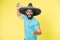 Mexican party concept. Man cheerful happy face in sombrero hat celebrating yellow background. Guy with beard looks