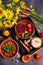 Mexican spicy food with beans, corn, tomatoes and chili, boiled rice, paprika on a dark wooden background. View from above. Still