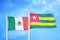 Mexico and Togo two flags on flagpoles and blue cloudy sky