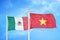 Mexico and Vietnam two flags on flagpoles and blue cloudy sky