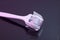 Mezoroller, dermaroller, mesotherapy skin tool. A mesoroller with a white handle and a pink rabbit on a dark mirror background. Ro