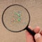 Micro plastic under magnification, magnifying glass. Invisible micro plastic in the sand. Conceptual image