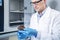 Microbiologist hand cultivating a petri dish whit inoculation loops, beside autoclave.