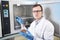 Microbiologist hand cultivating a petri dish whit inoculation loops, beside autoclave.