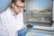 Microbiologist hand cultivating a petri dish whit inoculation loops, beside autoclave.