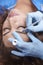 Microblading close-up, hands adding pigment to eyebrows, woman head face