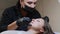 A microblading master is measuring woman`s eyebrows. Lady is lying at studio.