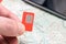 A microchip for telephone communication is on the background of a map and a smartphone. Phone sim card in hand is close up. Travel