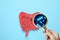 Microorganisms research. Woman with magnifying glass and paper intestine cutout on light blue, top view