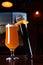 Microphone and a glass of beer on a dark background in the interior. The concept of a karaoke restaurant. Vertical photo on a dark
