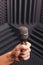 Microphone in hand, gray background with acoustic foam in studio