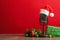 Microphone with Santa hat and decorations on grey table against red background. Christmas music