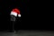 Microphone with Santa hat on grey stone table against black background. Christmas music