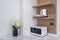 Microwave cooking machine on white marble counter with electric kettle on wooden cabinet interior kitchen decoration