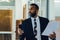 Mid adult bearded black man Entrepreneur Businessman wearing suit holding papers and smartphone walking in office