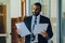 Mid adult bearded black man Entrepreneur Businessman wearing suit holding papers walking in office