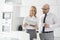 Mid adult business couple reading newspaper while having coffee in kitchen