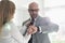 Mid adult businessman checking wristwatch while woman adjusting his tie at home