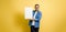 Mid adult cheerful businessman holding blank white banner template mock up and smiling at the camera while standing isolated