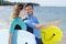 Mid adult couple stood by shore holding boogie boards