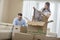 Mid-adult couple unpacking cardboard boxes in new home