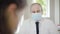 Mid-adult doctor in face mask consulting patient on Covid-19 pandemic. Blurred patient at front shaking head. Portrait