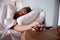 Mid adult man asleep in bed, reaching out to smartphone on the bedside table in the foreground