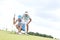 Mid-adult man looking at woman aiming ball on golf course