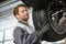 Mid adult technician adjusting car\'s tire in workshop