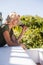 Mid adult woman drinking red wine while leaning on retaining wall in restaurant