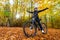 Mid-adult woman riding bicycle in city forest in autumnal scenery