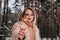 Mid age woman in winter forest with sparkler in hand. Woman in coat and sweater outdoors. Blonde girl in eyeglasses