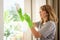 Mid aged woman cleaning and wiping window with spray bottle at home