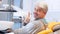 A mid aged young handsome man sitting in a dentists chair, he turns smiles into camera and shows a thumb up