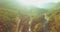 Mid air flight over fresh mountain river and meadow at sunny summer morning. Rural dirt road below.