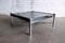 mid-century modern coffee table with smoked glass top and sleek chrome legs