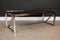 mid-century modern coffee table with smoked glass top and sleek chrome legs