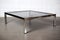 mid-century modern coffee table with smoked glass top and sleek chrome legs