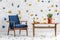 Mid-century modern, navy blue armchair and a retro wooden table in a white living room interior with lastrico pattern on the wall