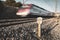 Mid-distance train moving out of a tunnel with the light in front of the sunset and kilometric railway signals along the tracks