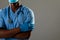Mid section of african american male health worker with arms crossed against grey background