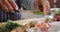 Mid section of asian senior woman putting chopped vegetables in a bowl in the kitchen