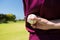 Mid section of baseball player holding ball behind back