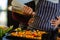 Mid section of biracial lesbian couple embracing and pouring oil on vegetables in kitchen