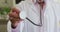 Mid section of caucasian senior male doctor holding stethoscope at home